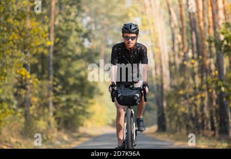 Turismo in bicicletta: L'uomo fa un giro in bicicletta attraverso la foresta. Il bikepacking, viaggiando in bicicletta, godendosi il giro in autunno Foto Stock