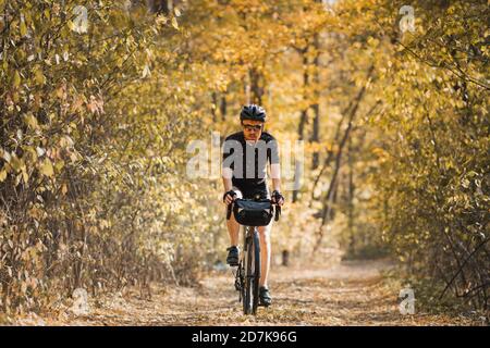 Turismo in bicicletta: L'uomo fa un giro in bicicletta attraverso la foresta. Il bikepacking, viaggiando in bicicletta, godendosi il giro in autunno Foto Stock