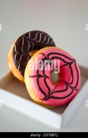 Due ciambelle in scatola bianca. Ciambelle rosa e cioccolato. Foto Stock