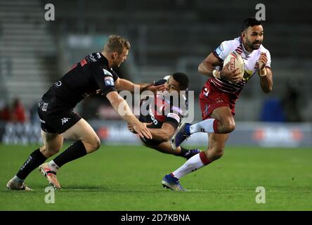 Il francese Bevan dei guerrieri di Wigan (a destra) si rompe da Joey Lussick di Salford Red Devils (a sinistra) e Kallum Watkins durante la partita della Betfred Super League al Totally Wicked Stadium, St Helens. Foto Stock