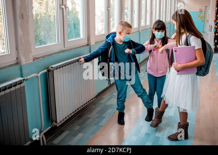 Gli studenti elementari si salutano con il gomito e il rubinetto per i piedi Foto Stock