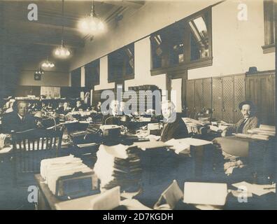 Antica fotografia del 1920 circa, gruppo di uomini in un edificio d'ufficio, possibilmente contabili. Posizione esatta sconosciuta, probabilmente New York City. FONTE: FOTOGRAFIA ORIGINALE Foto Stock