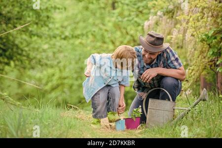 Piantando fiori. Rendere il pianeta più verde. Piante crescenti. Prendersi cura di piante. Ragazzo e padre in natura con annaffiatoio. Attrezzi di giardinaggio. Papà che insegna piante di cura di piccolo figlio. Piccolo aiutante in giardino. Foto Stock