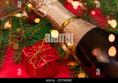 Cartolina di Natale con albero di Natale, champagne, scatola regalo rossa, primo piano delle attrazioni. Bello, Natale luminoso, sfondo di nuovo anno Foto Stock