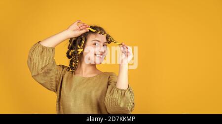 felicità dell'infanzia. ragazza felice nei curlers dei capelli che giocano il salone del parrucchiere. Punte facili che fanno la acconciatura per i bambini. Attrezzi per la cura dei capelli e accessori per i capelli. Posa del bambino con i arricciacapelli. Foto Stock