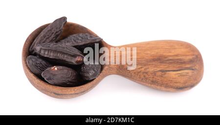 Fagioli tonka in cucchiaio di legno, isolati su sfondo bianco. Fagiolo di Dipteryx odorata, cumaru o kumaru. Fagioli tonka dall'aroma fresco. Foto Stock