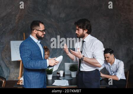 Diversi colleghi maschi amichevoli che parlano camminando nel corridoio moderno dell'ufficio, giovani uomini d'affari afroamericani e caucasici che discutono Foto Stock
