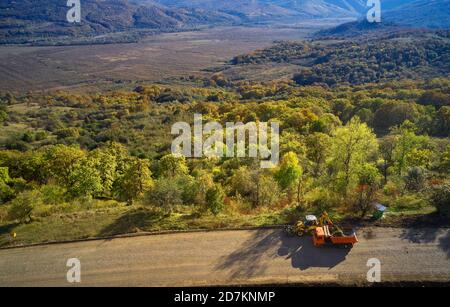 Almaty, Kazakhstan - 13 maggio 2019 - i lavoratori della strada stanno dipingendo la linea bianca sulla strada di montagna. Coni stradali con strisce rosse e gialle sullo sfondo, stand Foto Stock