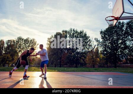 Due street basket i giocatori che giocano duro su corte Foto Stock