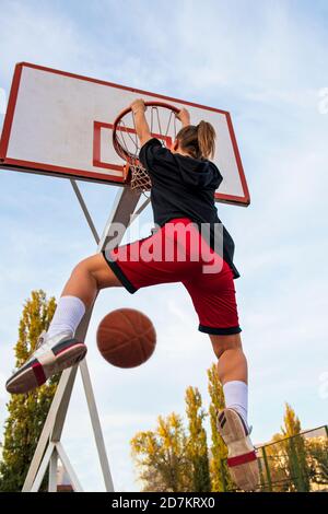 Femmine che giocano a basket sul campo di strada. Donna streetball giocatore che fa punk slam in un gioco di basket. Foto Stock