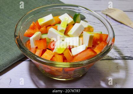 Insalata con cetriolo vegetale, pomodori e formaggio in recipiente trasparente Foto Stock