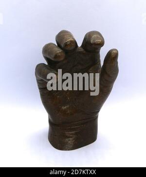 Foto di una scultura a mano del bambino in bronzo e fortemente illuminata su sfondo bianco Foto Stock