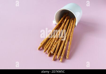 Bastoncini di pane bussati sopra la tazza bianca sullo sfondo rosa con spazio per la copia Foto Stock