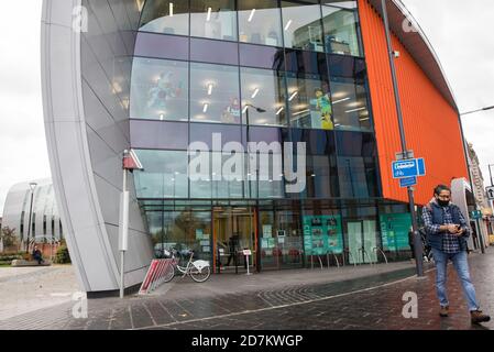 Slough, Regno Unito. 23 ottobre 2020. Un uomo all'esterno dell'edificio Curve indossa una copertura facciale per prevenire la diffusione del coronavirus. Il governo ha annunciato che Slough cambierà il suo status di livello di allarme COVID da livello 1 Medio Alert a livello 2 High Alert con effetto dalle 00:01 di sabato 24 ottobre, a seguito di un aumento sostenuto dei casi COVID-19, con conseguente tasso di infezione di 153 casi ogni 100,000. Credit: Mark Kerrison/Alamy Live News Foto Stock