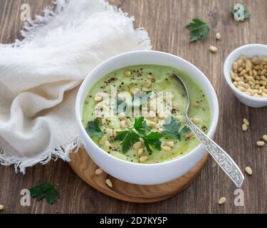 Zuppa di purea di cavolfiore con prezzemolo e pinoli in un recipiente bianco su un tavolo di legno. Cibo dieta delizioso Foto Stock