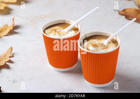 Tazze di carta con gustoso latte di zucca e spezie su tavola grigia. Primo piano. Foto Stock