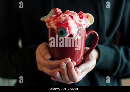 Donna che tiene la tazza con bevanda di Halloween spooky Foto Stock