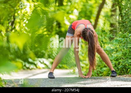 Atleta runner donna stretching facendo gamba stretch Warm-up jogging per correre all'aperto primavera estiva. Foto Stock