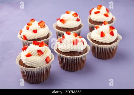 Deliziosi e gustosi muffin al cioccolato con fragole su sfondo lilla Foto Stock