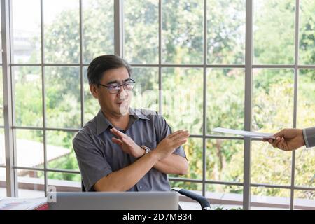 La mano che consegna documenti a un uomo asiatico di mezza età addolorante con la cattiva notizia: Imprenditori disperati vengono licenziati, nascosti, piangendo, delusi Foto Stock