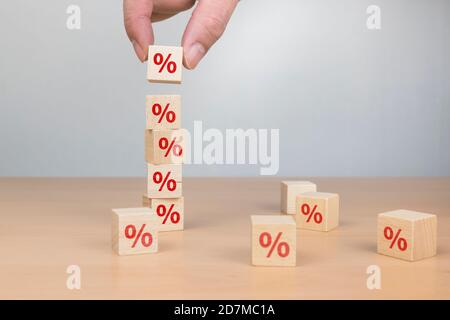 Uomo di affari mano mettendo legno cubo blocco con simbolo percentuale icona. Tasso di interesse, finanziario, classifica e concetto di tassi ipotecari Foto Stock