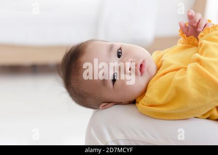 Un bambino asiatico si stende sul grembo della madre. Foto Stock