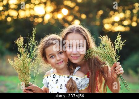 Due piccole ragazze carino abbracciando e sorridendo in campagna. Ragazzi felici che trascorrono del tempo all'aperto Foto Stock