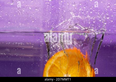 Primo piano di succo d'arancia su sfondo viola Foto Stock