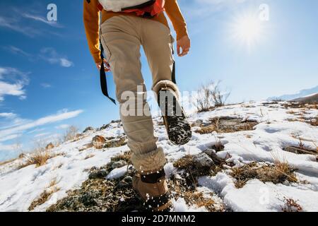 Lady escursionista va in salita su una superficie innevata. Foto closeup delle gambe della donna Foto Stock