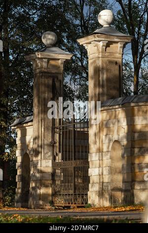 L'antica porta d'ingresso neoclassica ornata del maniero Tyshkevich nel vicolo del parco è illuminata dal sole serale in autunno a Traku Voke, Lituania Foto Stock