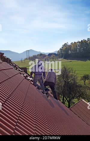 Appaltatori del tetto che posano le nuove piastrelle su un fienile. Foto Stock