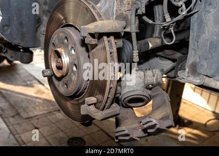 Pinza del freno anteriore smontata sulla vettura, che si trova sul martinetto per auto in officina. Foto Stock