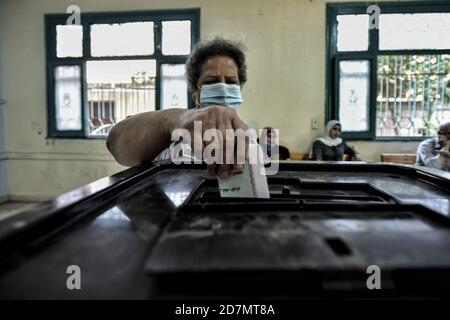 Giza, Egitto. 24 Ott 2020. Una donna lancia il suo voto in una casella elettorale all'interno di una stazione elettorale del distretto di al Omrania durante il primo turno della prima fase delle elezioni parlamentari egiziane. Credit: Sayed Hassan/dpa/Alamy Live News Foto Stock