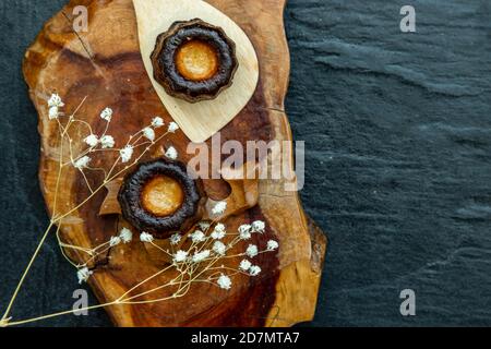 Cannelés (Canelés) de Bordeaux la ricetta è una piccola pasta con rum e vaniglia su un piatto di legno. Dolce tradizionale francese con gustosi spuntini. Top vi Foto Stock