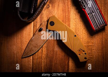 coltello pieghevole su una superficie di legno con accessori . Foto di alta qualità Foto Stock