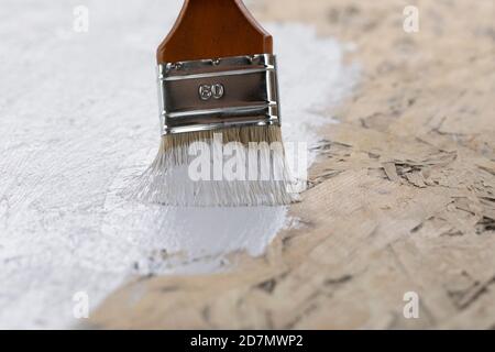 primo piano della spazzola con vernice bianca sulla superficie di legno Foto Stock