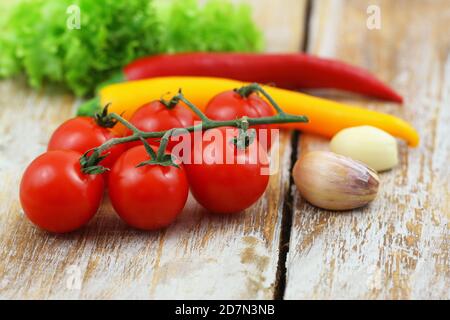 Selezione di ingredienti per cucinare: Pomodori ciliegini, spicchi d'aglio e peperoncini su superficie di legno Foto Stock