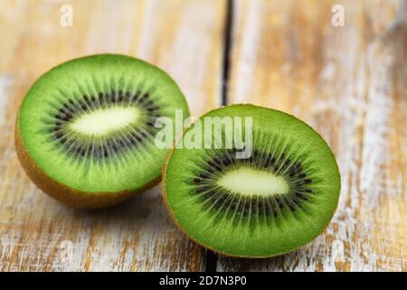 Primo piano di due metà succose e mature di kiwi superficie in legno Foto Stock