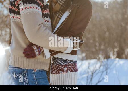 Un uomo e una donna in pullover caldi tengono le mani su una passeggiata invernale. Foto Stock