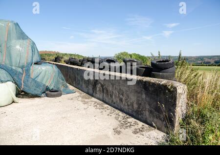 Pila o pila di balle di fieno e scartato vecchia gomma Pneumatici in campagna in Germania Foto Stock