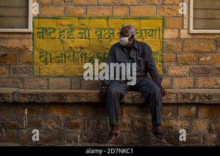 Jaisalmer, Rajasthan / India - settembre 24 2020 : uomo anziano seduto e mantenendo le linee guida di distanziamento sociale in attesa di pick up Foto Stock