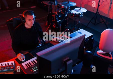 Un giovane tecnico di suono che lavora e mescola musica all'interno del studio Foto Stock