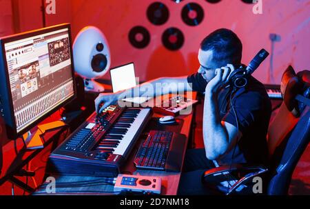 Un giovane tecnico di suono che lavora e mescola musica all'interno del studio Foto Stock