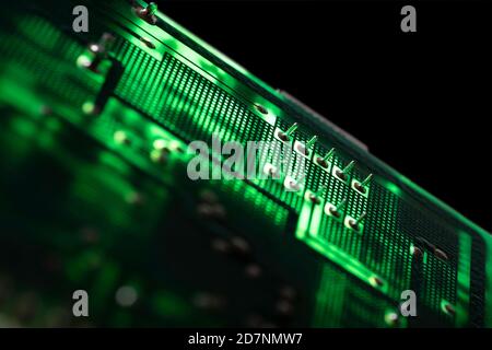Scheda elettronica verde illuminata con molti componenti elettrici e collegamenti. Immagine futura isolata su sfondo nero Foto Stock