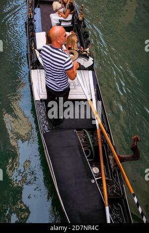 Gondoliere e turisti in gondola in un bel piccolo canale con le tradizionali case veneziane colorate - mattina tranquilla con strade vuote a Venezia, Foto Stock