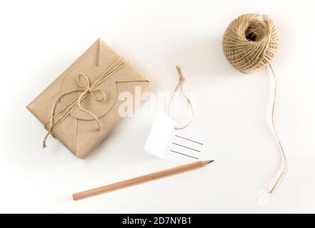 Scatola regalo marrone avvolta in carta kraft e canapa rustica bobina di cavo come stile rustico naturale con carta e matita per scrivere la tua nota Foto Stock