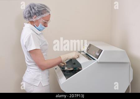 Infermiere femmina che esegue la sterilizzazione di strumenti odontoiatrici in autoclave Foto Stock