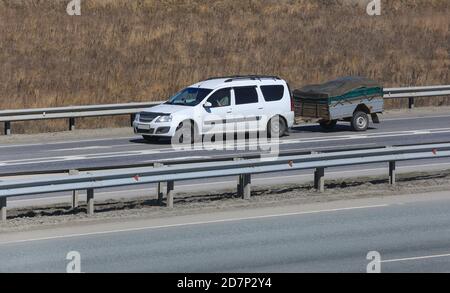 l'auto con il rimorchio va su un'autostrada di campagna Foto Stock