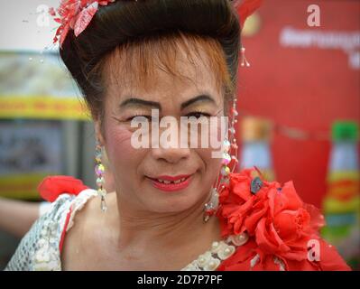 Medio invecchiato vestito thailandese cross-dressing genere queer (kathoey) sorride per la macchina fotografica a Chinatown durante il Capodanno cinese. Foto Stock