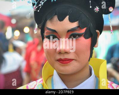 L'esecutore cinese tailandese in costume femminile con la maschera painted tradizionale dell'opera di Pechino pone per la macchina fotografica alla parata di strada di Capodanno cinese colorata. Foto Stock